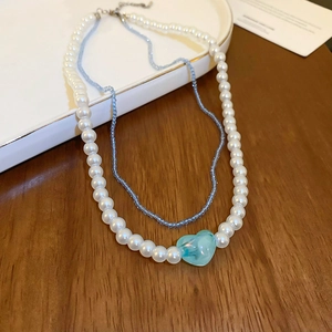 Detailed close-up of double-layer choker with faux pearls and blue heart charm