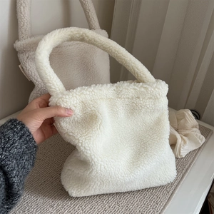 Detail view of a soft white plush faux fur handbag with a thick textured top handle