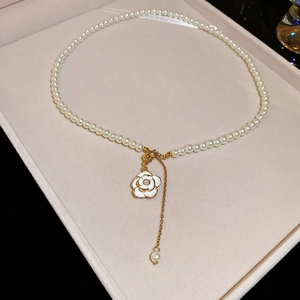 Macro detail of camellia pendant and pearls in a velvet jewelry box