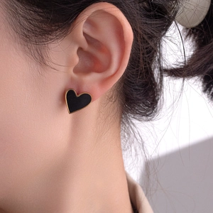 Minimalist black heart stud earrings with 18K gold plated trim on model ear