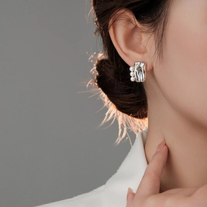 Detailed view of silver irregular textured earrings with vertical triple pearl accents