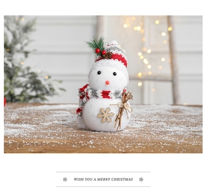 Close-up of a plush Christmas snowman with a red striped hat and scarf on a festive table