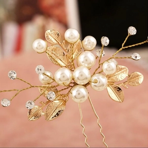 Macro detail of bridal U-shaped hair pin with pearls, gold leaves and crystal rhinestones