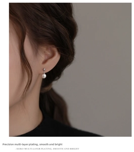 Close-up of elegant pearl drop earrings with silver finish on model's side profile