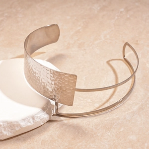 Detail of silver double-layered hammered metal choker on a white stone background