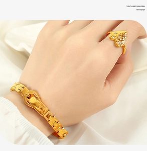 Detail of gold belt buckle bracelet and heart diamond ring on white silk background
