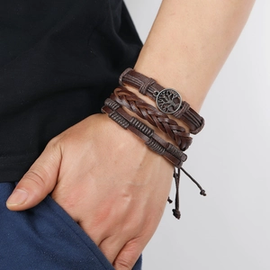 Detail of dark brown leather wrap bracelet with a metal Tree of Life charm on wrist