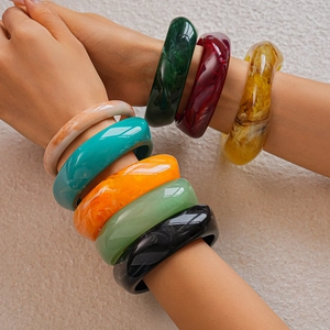 Detailed view of colorful marbled resin bangles worn in stacks on model arms