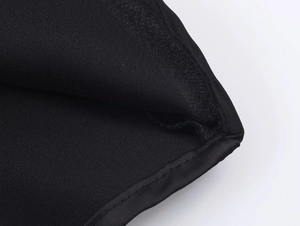 Macro shot of fine machine stitching and smooth satin texture on black camisole hem