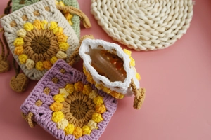 Detail of handmade crochet sunflower pouches in beige and purple with drawstring closure
