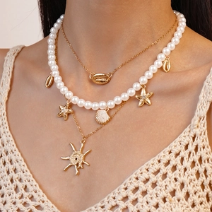 Close-up of a three-piece gold-toned beach necklace with shell and starfish charms