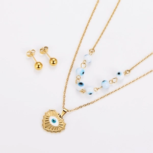 Detail view of a gold double-layer necklace with blue evil eye beads and heart pendant