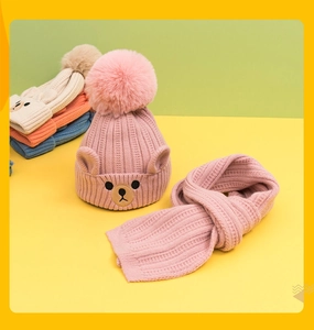 Detailed close-up of pink children's knitted bear hat with pom-pom and matching scarf
