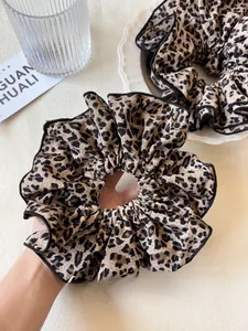 Dettaglio di due elastici scrunchie oversize con stampa leopardata e bordi neri in raso