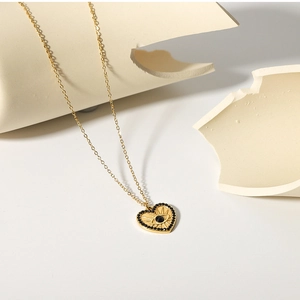 Macro detail of 18K gold stainless steel heart pendant with black evil eye and zircons