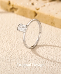 Bague en argent moissanite taille émeraude posée sur pierre naturelle sous lumière douce