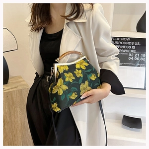 Detail of vintage green cheongsam handbag with yellow floral embroidery and wooden handle
