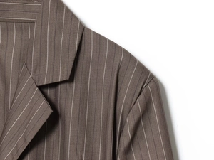 Détail du revers de blazer marron à fines rayures avec épaulettes et texture de tissu