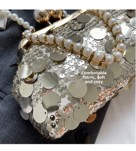 Detailed close-up of golden and silver sequins with pearl bead handle on luxury evening bag
