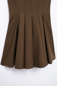 Close-up detail of the brown houndstooth pattern and pleated texture of the mini dress