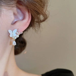 Close-up of butterfly drop earring with pearls and zircon on model's ear