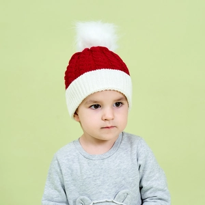 Kids knitted Christmas hat with pompom and red-white cable knit design for winter warmth