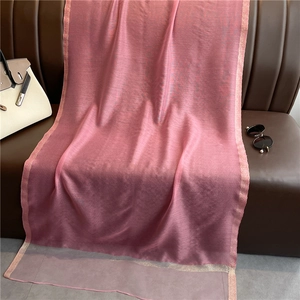 Detalle de textura de bufanda de seda rosa con brillo sutil sobre un sofá