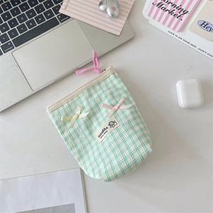 Macro shot of green plaid makeup bag with bow detailing and a zipper closure