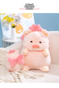 Detail view of two soft pink plush pig toys in small and large sizes on a sofa