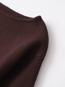 Makroaufnahme von dunkelbraunem Strickstoff mit Details an Ausschnitt und Schulter
