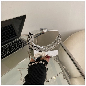 Macro detail of silver mirror square bag with chunky chain handle and sleek metal finish