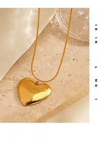 Macro detail of polished heart pendant on snake chain over aesthetic stone background