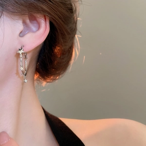 Silver star drop hoop earring worn by a model showing high-end fashion design details