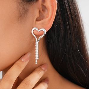 Close-up of elegant silver heart stud earrings with sparkling zircon tassel chains on model