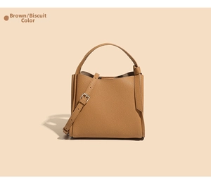 Detail of biscuit brown pebbled leather bucket bag with top handle and metal buckle strap