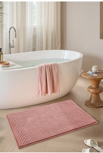 Close-up of pink chenille bath mat with textured absorbent surface on a wooden floor