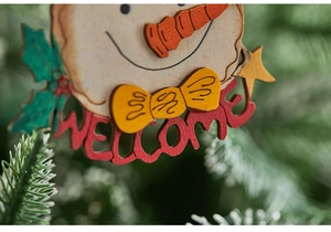 Macro detail of hand-painted wooden snowman ornament with festive Welcome sign on Xmas tree