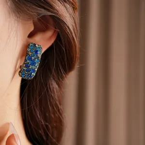 Boucles d'oreilles bohèmes rectangulaires avec cristaux bleus et base dorée sur modèle