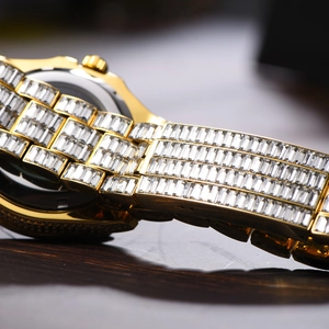 Close-up of luxury gold watch band and case back fully iced out with square crystals