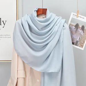 Close-up of soft light blue cotton linen scarf draped on a beige blazer and wooden hanger