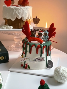 Detail of Christmas cake toppers with cute bears and red antlers on white cream