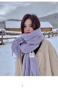 Close-up of lilac knitted scarf with handmade label against a winter snowy background