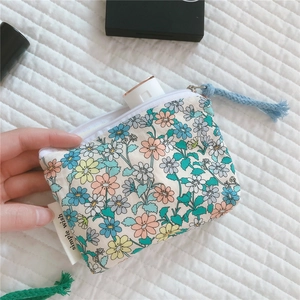 Detailed shot of floral cotton mini pouch with zipper tassel holding a small skincare tube