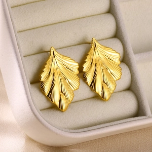 Macro shot of gold leaf earrings with textured veins on a white velvet display