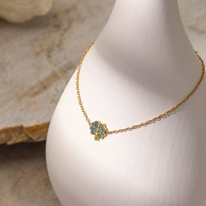 Makroaufnahme von Kleeblatt Armband mit blauen Kristallen auf weißer Vase