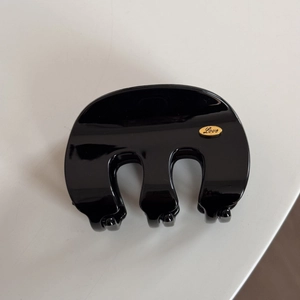 Detail of a large black claw clip featuring a gold oval Love engraved plate decoration