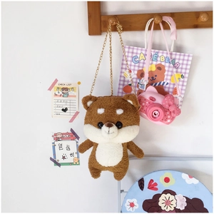 Detailed view of Shiba Inu plush bag with golden chain hanging on a wooden hook
