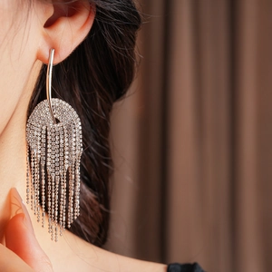 Gros plan de boucles d'oreilles pompons argentées avec strass portées par un mannequin