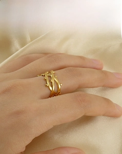 Detail of cross-line design 18K gold plated stainless steel ring on silk background