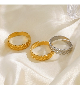 Close-up of twisted braided open rings in gold and silver finish on silk fabric